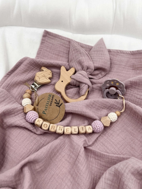 Personalizowana zawieszka do smoczka i szeleszczące uszka z muślinu to wyjątkowy zestaw dla niemowlęcia. Idealny prezent dla noworodka, wykonany z naturalnych materiałów. Idealny prezent na narodziny, baby shower lub chrzciny.