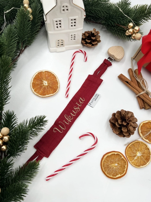 Personalizowana zawieszka do smoczka z haftowanym imieniem i drewnianym klipsem. Praktyczny dodatek do wyprawki niemowlęcej i wyjątkowy prezent dla noworodka.