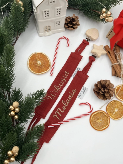 Personalizowana zawieszka do smoczka z haftowanym imieniem i drewnianym klipsem. Praktyczny dodatek do wyprawki niemowlęcej i wyjątkowy prezent dla noworodka.