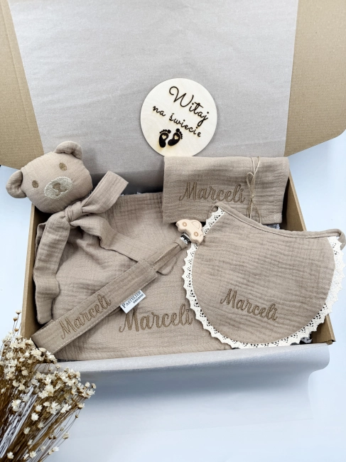 Personalizowany box dla noworodka z misiem z muślinu, zawieszką do smoczka, śliniaczkiem i pieluszką z imieniem. Idealny prezent na narodziny dziecka, baby shower, chrzciny lub pierwszą wizytę.