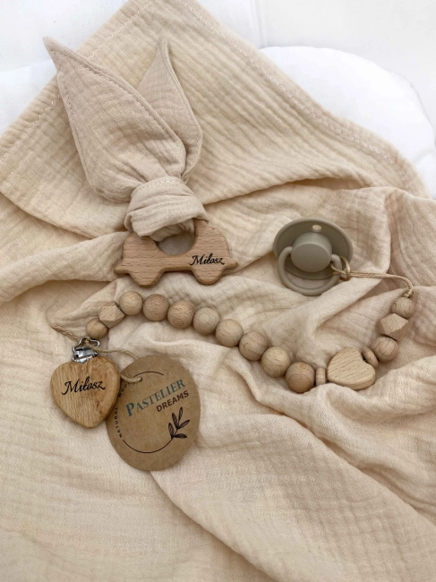Personalizowana zawieszka do smoczka i szeleszczące uszka z muślinu to wyjątkowy zestaw dla niemowlęcia. Idealny prezent dla noworodka, wykonany z naturalnych materiałów. Idealny prezent na narodziny, baby shower lub chrzciny.