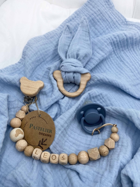 Personalizowana zawieszka do smoczka i szeleszczące uszka z muślinu to wyjątkowy zestaw dla niemowlęcia. Idealny prezent dla noworodka, wykonany z naturalnych materiałów. Idealny prezent na narodziny, baby shower lub chrzciny.