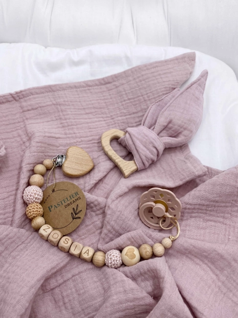 Personalizowana zawieszka do smoczka i szeleszczące uszka z muślinu to wyjątkowy zestaw dla niemowlęcia. Idealny prezent dla noworodka, wykonany z naturalnych materiałów. Idealny prezent na narodziny, baby shower lub chrzciny.